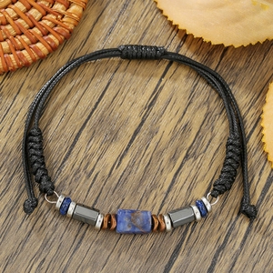 Detail van verstelbare zwarte koordarmband met blauwe steen en metalen afstandhouders