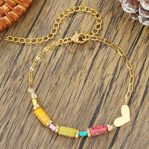 Pulsera bohemia de cuentas arcoíris con dije de corazón dorado sobre madera rústica