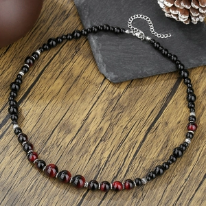 Collana da uomo con perle in occhio di tigre rosso e ossidiana nera su legno scuro