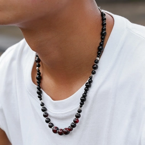 Dettaglio della collana da uomo con perline occhio di tigre rosso e pietre nere