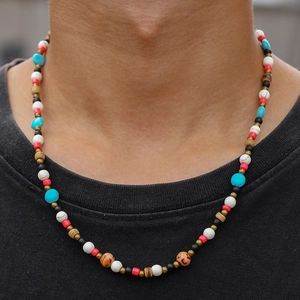 Gros plan d'un collier de perles bohème avec perles turquoise et marbre sur un modèle masculin