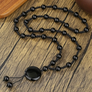 Gothic Onyx Perlenkette mit rundem Anhänger und Quaste auf hölzernem Hintergrund