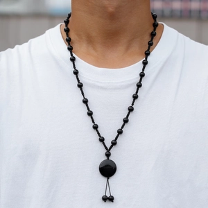 Detail einer gotischen Onyx-Halskette mit rundem Anhänger und Quasten am Model
