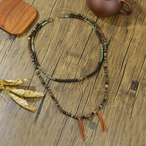 Bohemian double-layer beaded necklace with coin pendant and orange tassels on wood