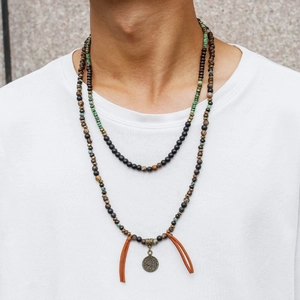 Detail view of Bohemian layered beaded necklace with coin pendant and leather tassels