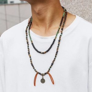 Detail of bohemian men's beaded necklace with coin pendant and brown leather tassels
