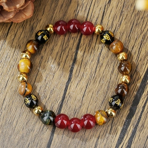 Tigerauge- und Karneol-Perlenarmband mit goldenen Mantra-Anhängern auf Holzgrund