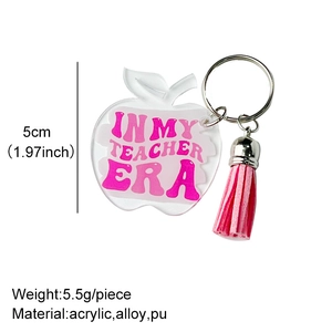 Detail of apple keychain with IN MY TEACHER ERA text and pink tassel charm decoration