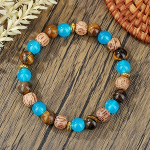 Ethno-Perlenarmband mit Tigerauge-Steinen und blauen Perlen auf dunklem Holzhintergrund