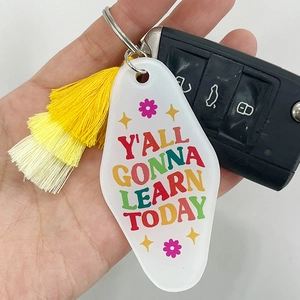 Acrylic teacher keychain with pink tassel and Y'ALL GONNA LEARN TODAY text held by hand