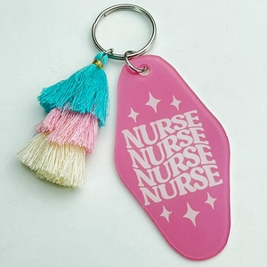 Detail of pink acrylic nurse keychain with three-layer tassel and retro lettering