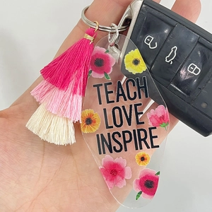 Acrylic floral teacher keychain with pink tassel featuring Teach Love Inspire text