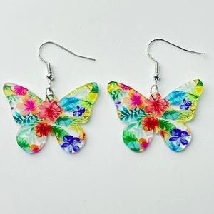 Détail des boucles d'oreilles papillon en acrylique avec motifs floraux et crochets argentés