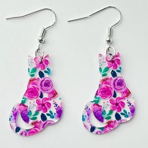 Détail de boucles d'oreilles chat en acrylique avec motifs de roses roses et violettes et crochets