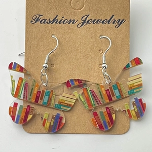 Detail view of butterfly shaped clear acrylic earrings with vintage bookshelf pattern prints