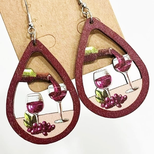 Detailed view of teardrop wooden earrings featuring wine bottle and grape graphics
