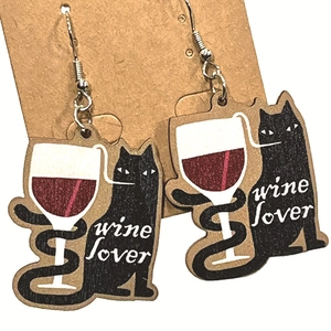 Detail of wooden drop earrings featuring a black cat toast and wine lover engraving