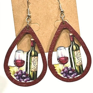Close-up of teardrop wooden earrings with wine bottle and grape prints on craft card