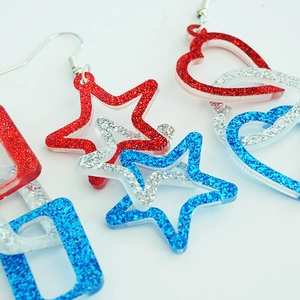 Macro detail of red, white, and blue glitter heart and star patriotic earrings