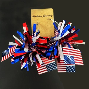 Détail de boucles d'oreilles pompons rouge, blanc et bleu avec motif drapeau USA
