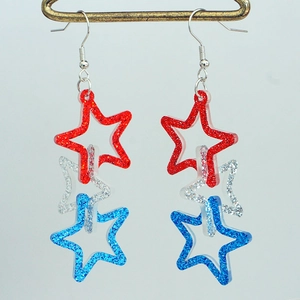 Close-up of glitter patriotic star earrings featuring red white and blue tiered pentagrams