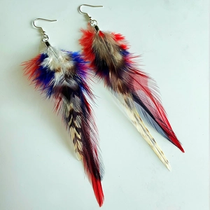 Detailed view of layered bohemian earrings with colorful natural feathers and silver hooks