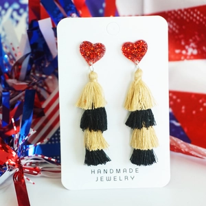 Detail of layered gold and black tassel earrings with a red sequined heart top