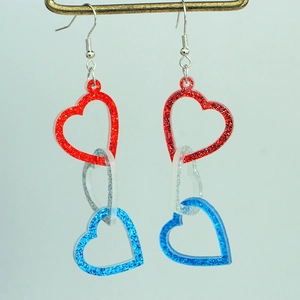 Macro detail of red silver blue glitter heart shaped dangle earrings with triple loop design