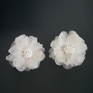 Detail von zarten weißen Organza Blumen-Ohrringen mit Perlenbesatz auf schwarzem Hintergrund