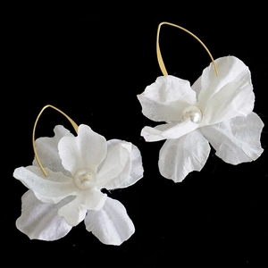 Nahaufnahme eleganter weißer Stoffblumenohrringe mit Perlen und Goldhaken auf Schwarz