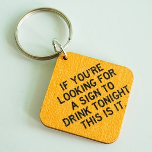 Macro shot of wooden keychain featuring engraved humorous quote for alcohol lovers