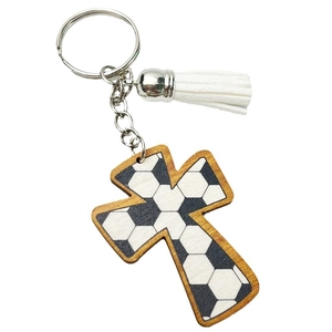 Detail of wooden cross keychain with soccer pattern and white tassel charm on ring