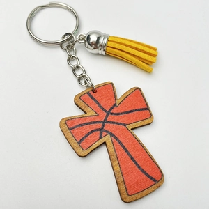 Detailed view of a wooden cross keychain with basketball texture and yellow tassel