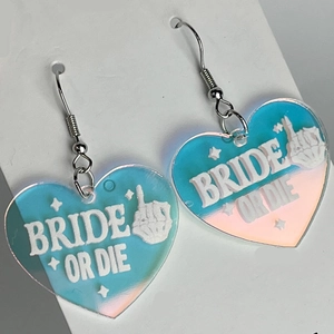 Detailansicht herzförmiger Acryl-Ohrringe mit blau-rosa Farbverlauf und Bride or Die Text