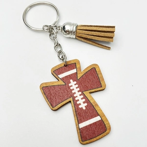 Macro shot of wooden cross keychain with football pattern and brown suede tassel