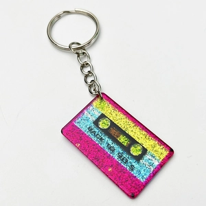Macro detail of retro cassette keychain with colorful glitter and Back to 90s slogan