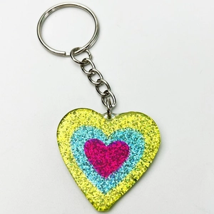 Close-up of heart-shaped glitter keychain with tricolor yellow, blue and pink layers