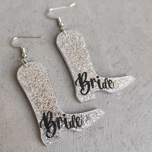 Detailansicht der silbernen Glitzer-Cowboystiefel-Ohrringe mit Bride-Schriftzug für Hochzeiten