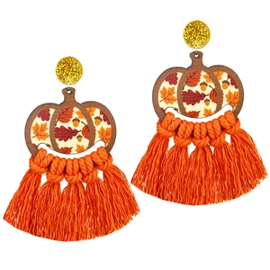 Close-up of bohemian pumpkin earrings with orange tassels and gold glitter studs