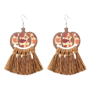 Detail of bohemian pumpkin wood earrings with coffee cotton tassels and autumn leaf patterns