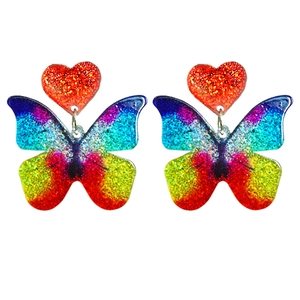 Macro detail of rainbow glitter acrylic heart and butterfly tassel drop earrings