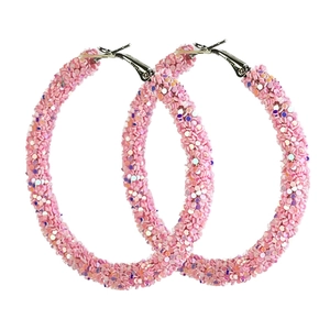 Macro detail of pink glitter hoop earrings featuring sparkling textured surface and silver clasp
