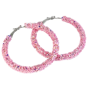 Macro detail of large pink glitter hoop earrings featuring vibrant shimmering sequins