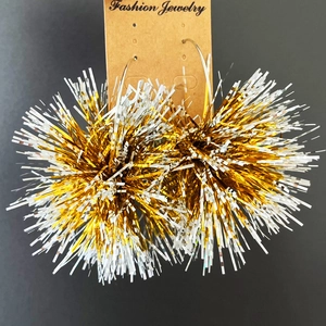 Close-up of gold and silver metallic fringe sphere earrings on a fashion display card