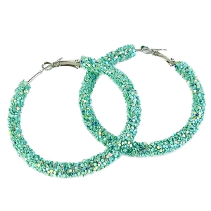 Close-up of mint green large glitter hoop earrings with sparkling metallic sequins