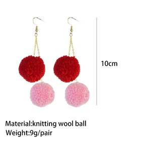 Detail view of 10cm long pink and red yarn ball drop earrings with gold chains