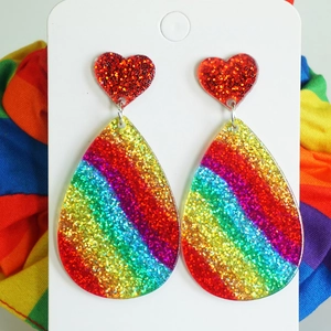 Detail of glitter rainbow heart and teardrop acrylic earrings on display card