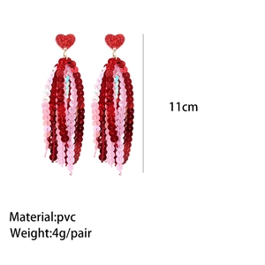 Détail des boucles d'oreilles pompons 11cm à paillettes roses et rouges avec cœurs