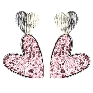 Détail de boucles d'oreilles cœur avec texture pailletée rose et motifs en métal argenté