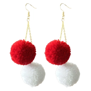 Detail view of red and white yarn pom-pom earrings with golden chain links
